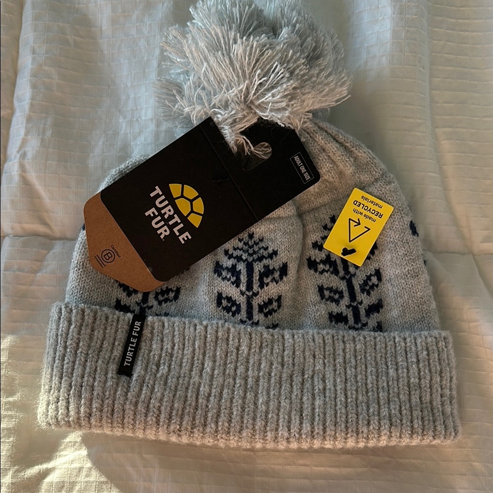 Gray knitted winter hat with pom-pom and floral pattern